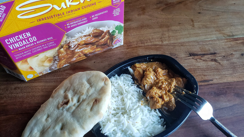 Container of Sukhi's Chicken Vindaloo on a wooden table with fork
