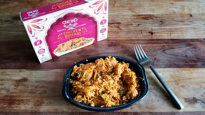 Bowl of Deep Indian Kitchen Chicken Biryani on a wooden table with fork