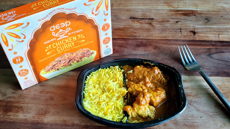 Bowl of Deep Indian Kitchen Chicken Curry on wooden table with fork