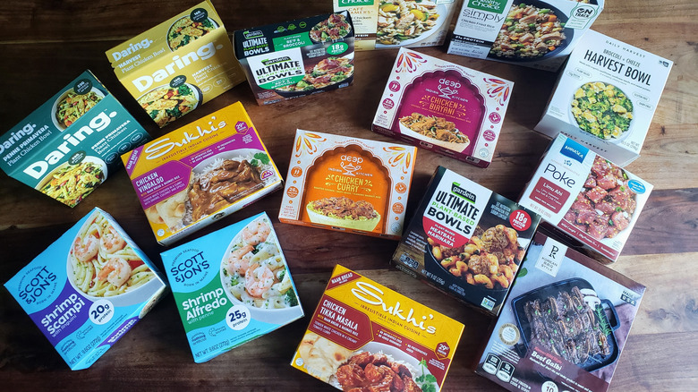 Assortment of high-protein frozen entrées on a wooden dining table