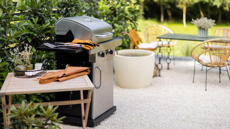 backyard grilling area with grill, side table, dining table, and lawn in background