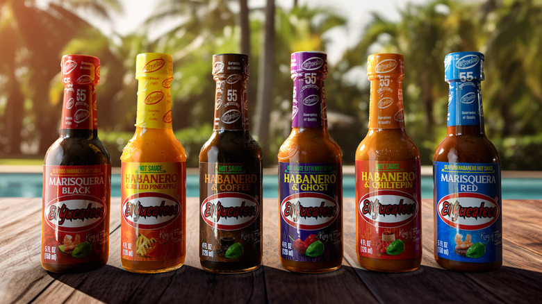 Six bottles of El Yucateco hot sauce displayed on a patio table