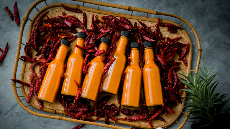 A wicker gift basket containing unlabeled bottles of hot sauce