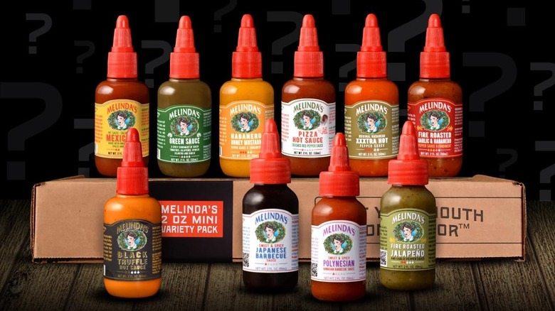 10 mini bottles of Melinda's hot sauce arranged on top of a gift box
