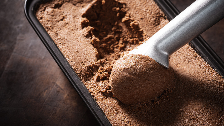Chocolate ice cream being scooped from a tub