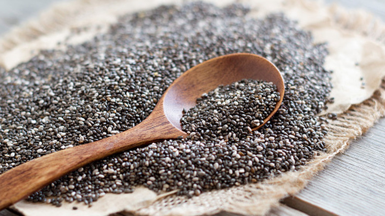A wooden spoon lying in a pile of dark chia seeds