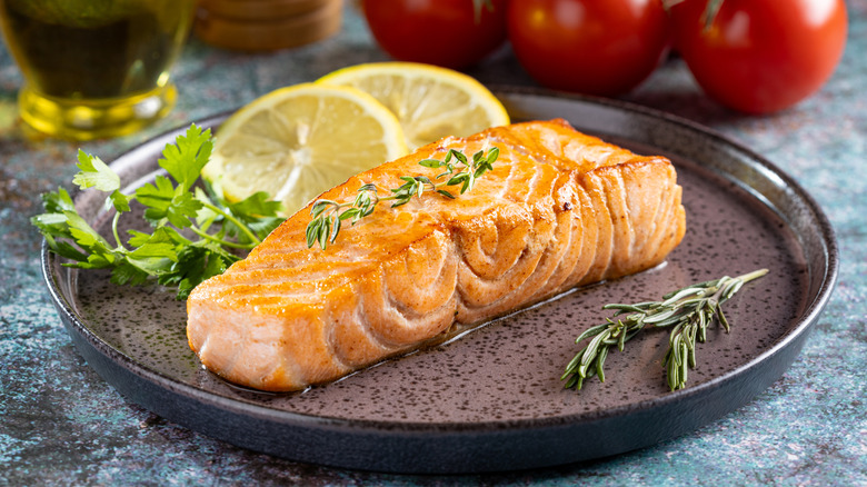 Grilled salmon on a plate with lemons and herbs