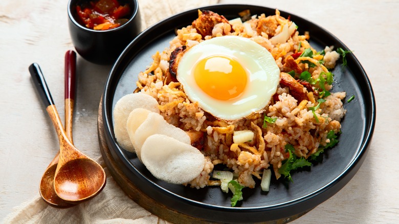 Plate of Nasi Goreng with prawn crackers and a fried egg on top