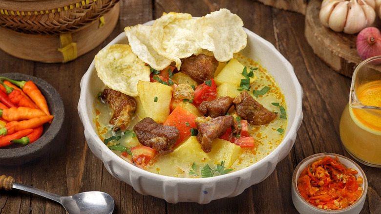 Bowl of Indonesian Soto Betawi beef soup with prawn crackers on top