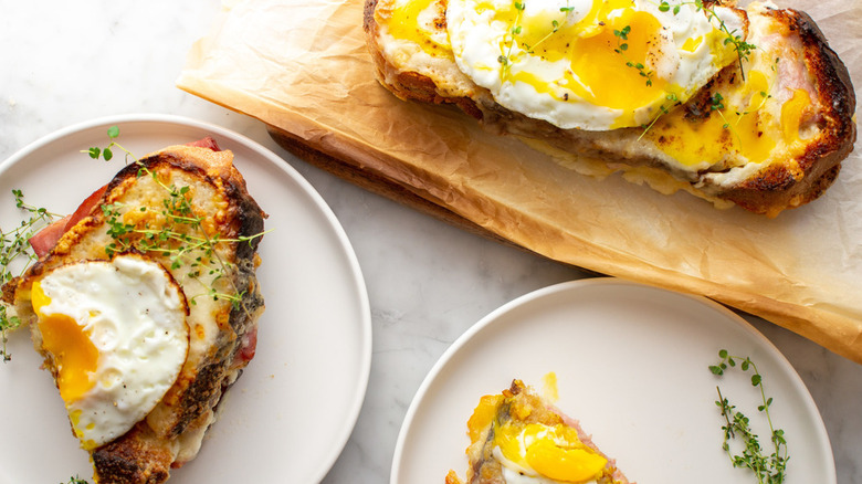 plate of croque madame next to chopping board with croque madame