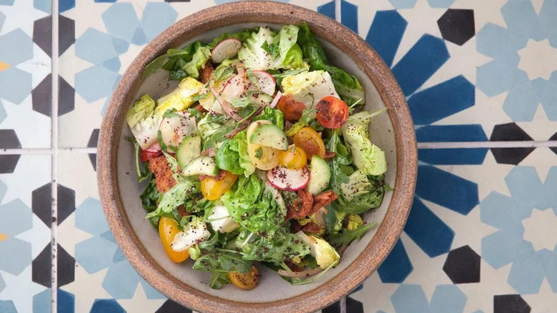 bowl of fattoush salad against blue patterned background