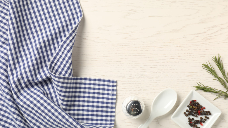 Gingham tablecloth and spices on white wooden flatlay