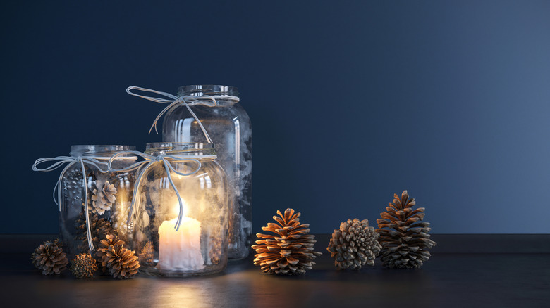 3 mason jars decorated with candles and pine cones