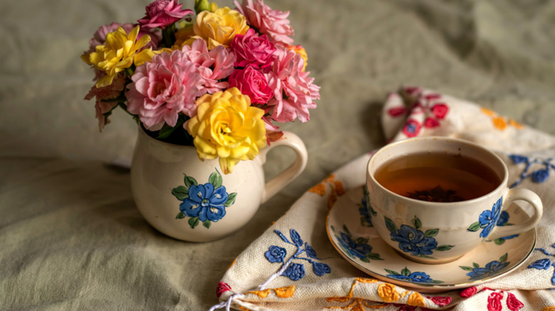 Colorful cup and flowers on a floral tea towel