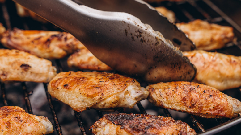 Raw chicken breast cut into slices on a wooden chopping board on a granite surface
