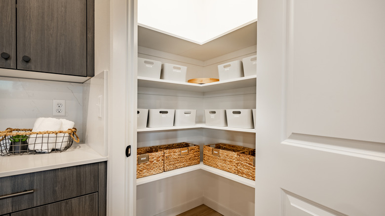 Open doors showing walk-in kitchen pantry with wicker baskets