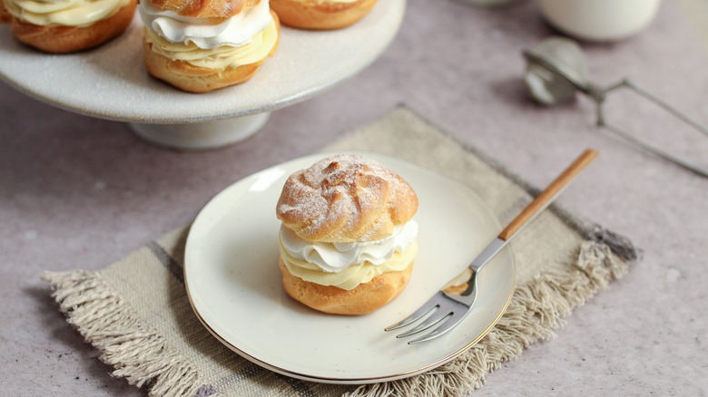 Cream puff on white plate with dessert fork