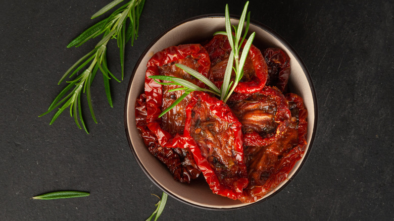A bowl of sundried tomatoes on black background