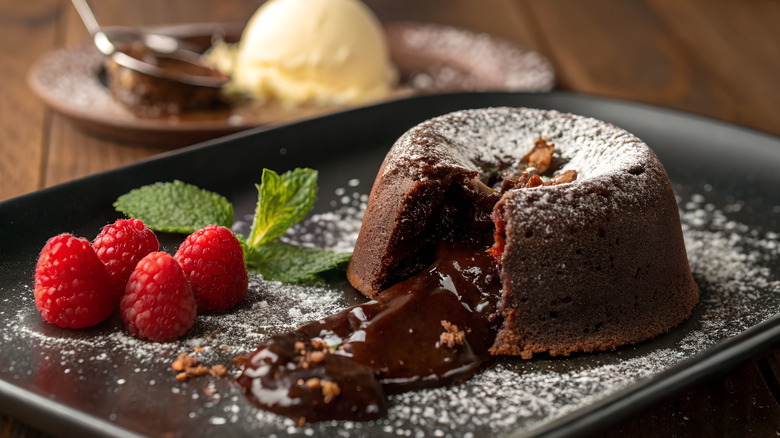 Oozing chocolate lava cake on a plate with raspberries