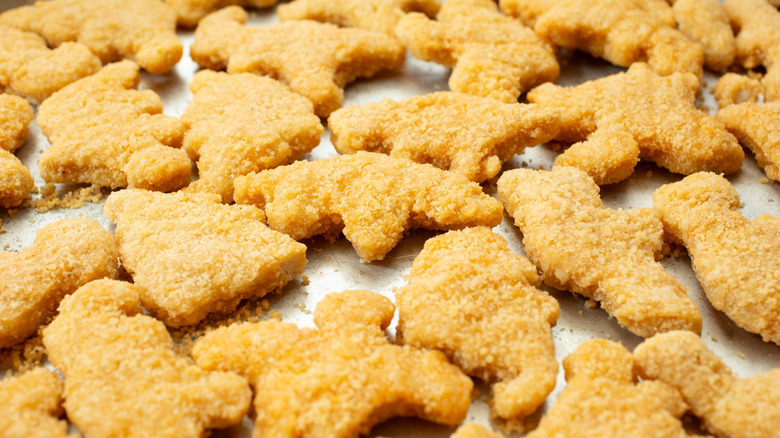 Dinosaur shaped chicken nuggets on a sheetpan