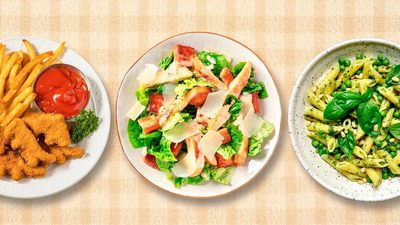 Plates of dino nuggets, Caesar salad, and pesto