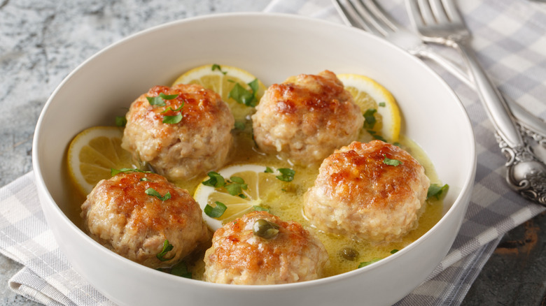 chicken meatballs in broth with lemon an capers in a bowl