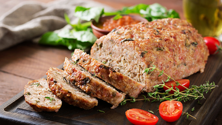 a ground turkey meatloaf with herbs, sliced on a wooden platter