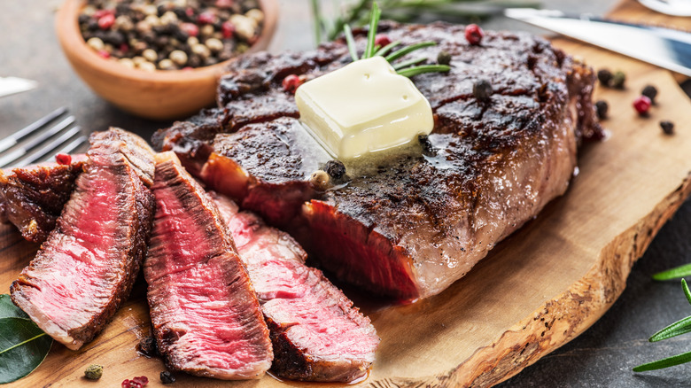 grilled and sliced ribeye steak with a large pat of butter on top