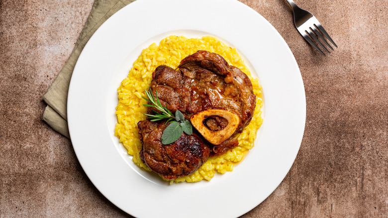 a large portion of osso bucco over yellow rice on a white plate