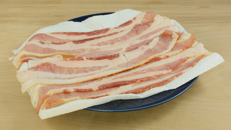 Bacon strips on kitchen towel-lined plate