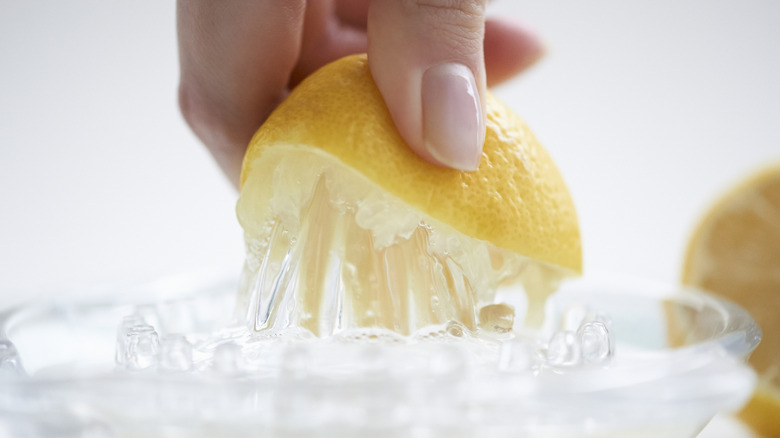 Hand pressing lemon onto juicer