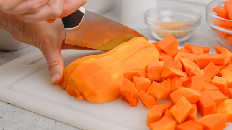 Chopping butternut squash on plastic cutting board