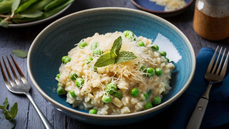 Bowl of risotto with peas, topped with grated Parmesan and sprig of mint