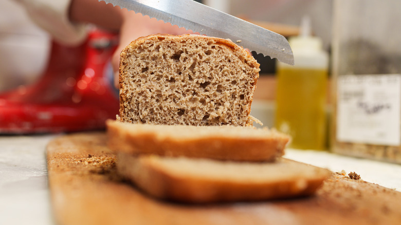 Slicing loaf of bread on wooden cutting board
