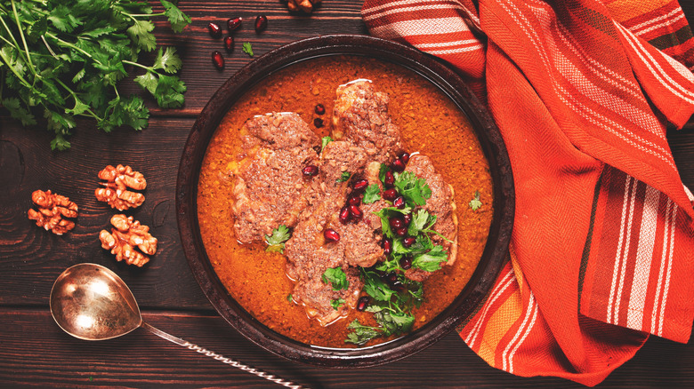 Fesenjan in black bowl with pomegranate seeds
