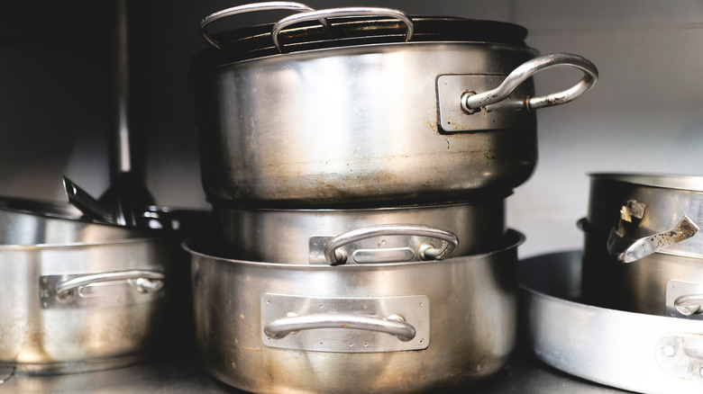 a messy stack of well-used pans on a shelf