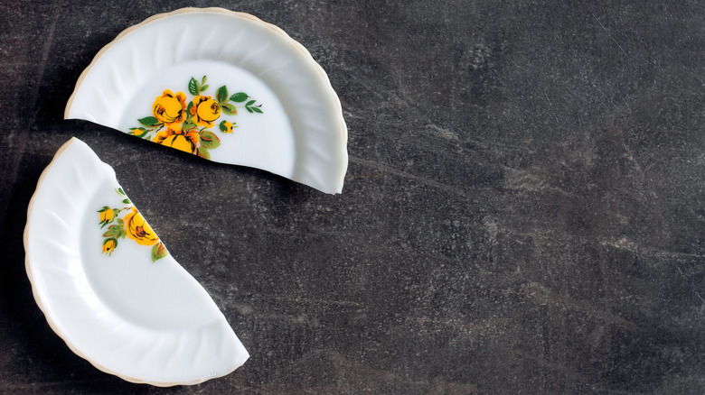 broken vintage plate with a yellow floral pattern and gold-trimmed outer edge, shown on a stone countertop