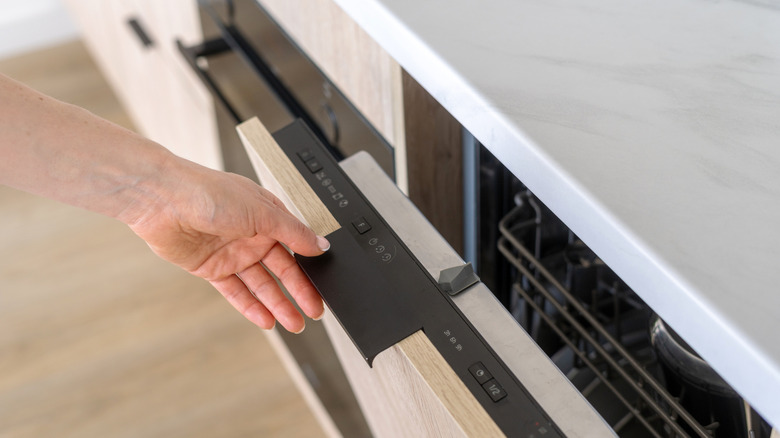 woman's hand opening dishwasher