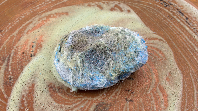 scrubbing a vintage copper pan with a steel-wool scouring pad