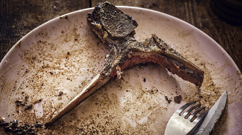 steak bone on a plate with a fork and knife