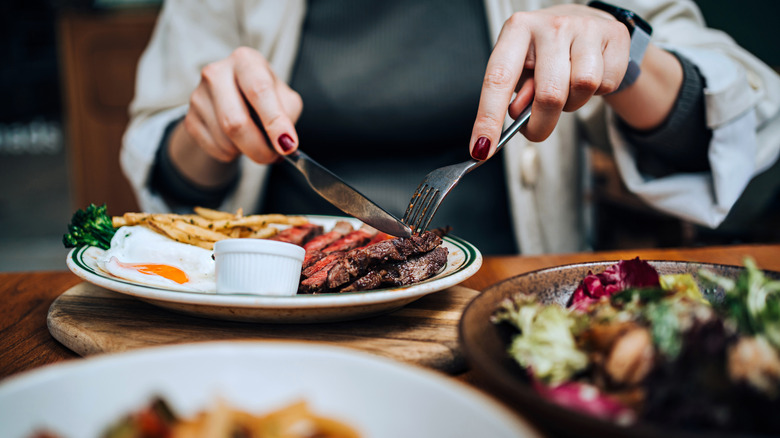 woman cutting steak on a plate
