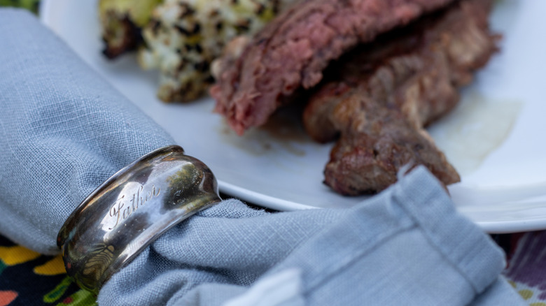 steak on a plate with a cloth napkin and napkin ring