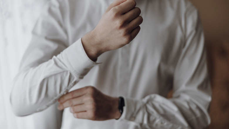 man getting dressed and buttoning his shirt