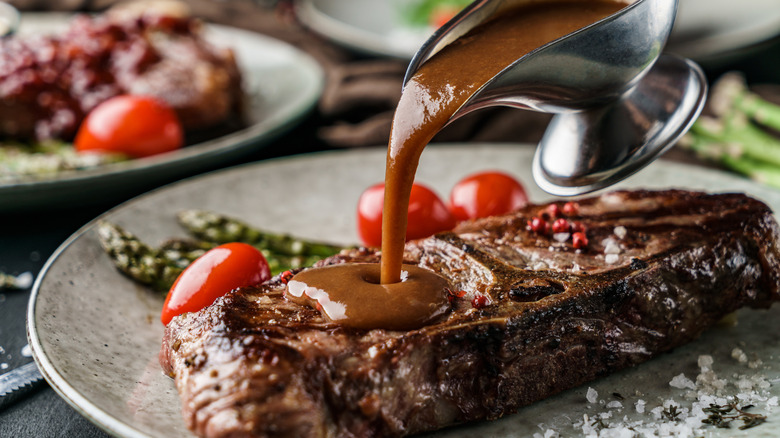 sauce being poured over steak on plate