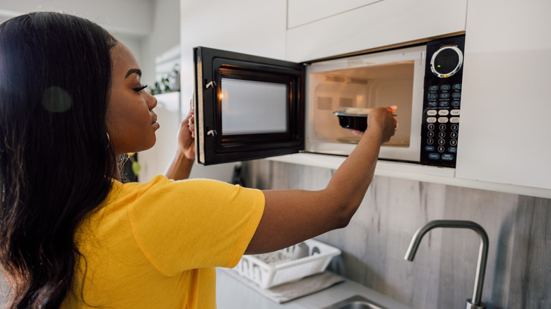 Person putting food into microwave