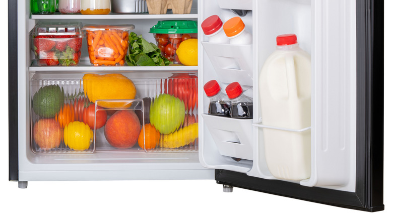 Fridge door containing milk bottles and soda