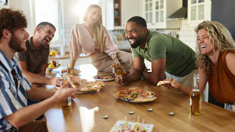 Group of five people having pizza and beer