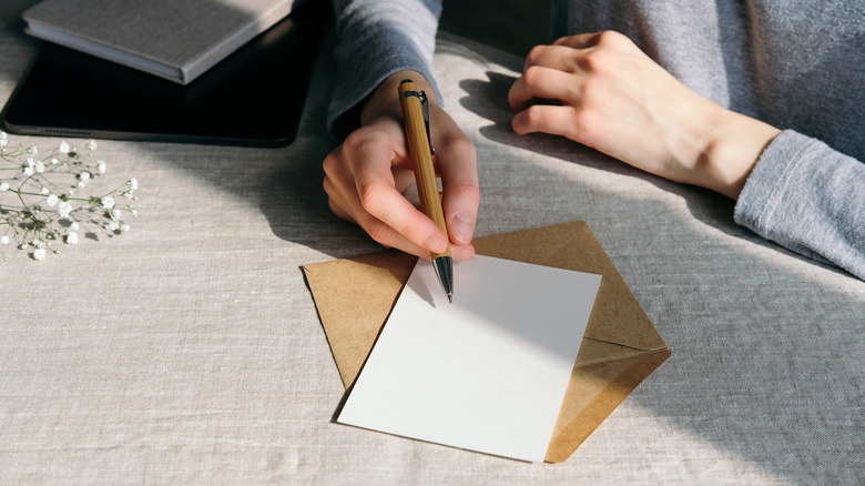 A hand holding a pen ready to write an invitation card