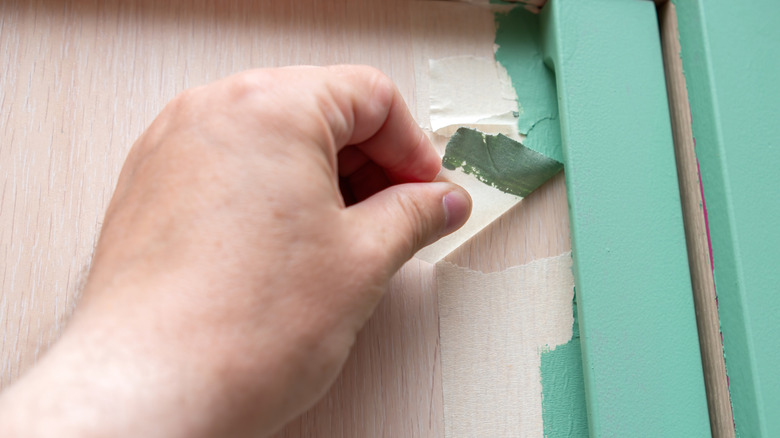 Hand removing masking tape after painting