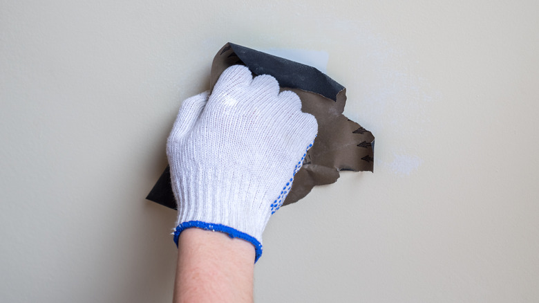 Close-up image of a hand running sandpaper on a wall